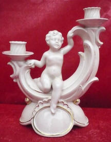Cherub sitting in the middle of two candleholders